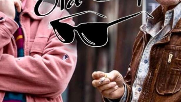 Zwei Männer stehen vor einer Wand, der ältere raucht eine Zigarette.