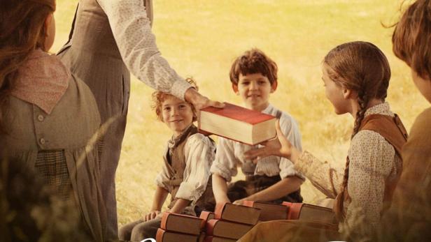 Eine Lehrerin umgeben von Kindern, die Bücher im Freien austauschen, möglicherweise eine Szene aus „Louise Violet“.
