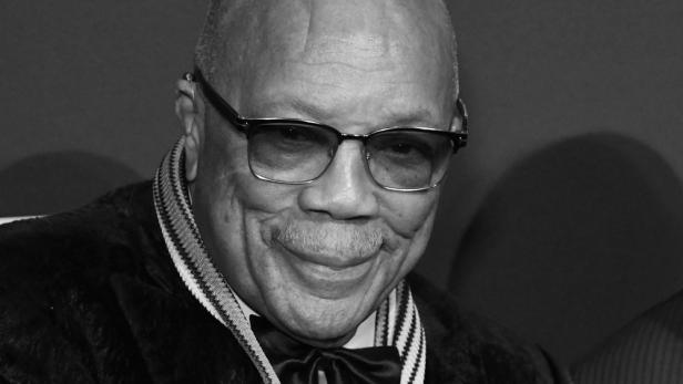 Schwarzweißporträt von Quincy Jones mit Brille und Fliege.