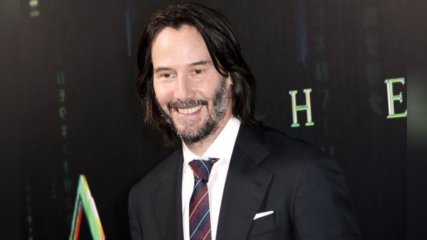 Keanu Reeves auf dem roten Teppich vor dem Hintergrund von „The Matrix“.