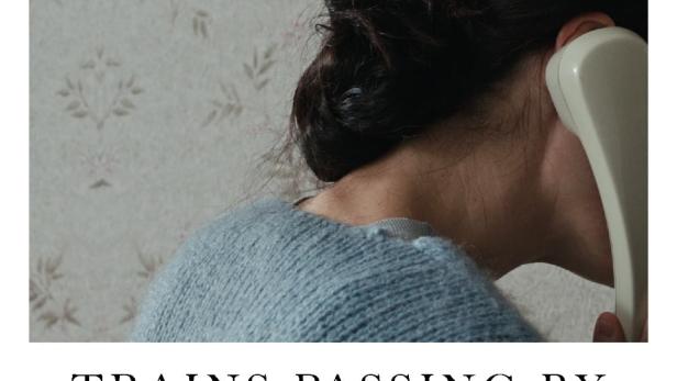 Eine Frau telefoniert mit einem alten Telefonhörer vor einer floralen Tapete.