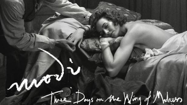 Ein Schwarzweißfoto des Filmplakats für „Modì“, das eine Frau zeigt, die auf einem Bett liegt, während ein Mann ihre Hand hält.