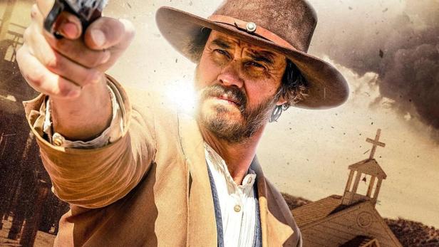 Ein Mann im Western-Stil zielt mit einer Pistole vor einer Kirche im Film „Ghosts of Red Ridge“.