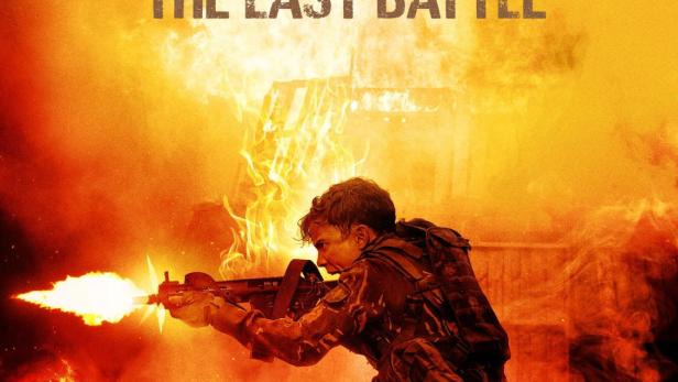 Ein Soldat feuert mit einem Maschinengewehr inmitten von Rauch und Flammen.