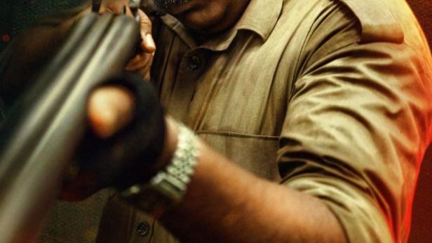 Ein Mann mit Schnurrbart zielt mit einem Gewehr in dem Film „Rifle Club“.