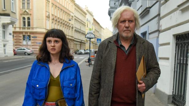 Ein junges Mädchen und ein älterer Mann gehen eine Straße entlang.