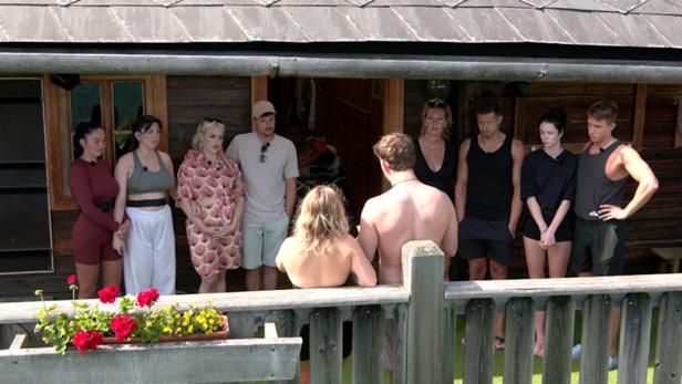 Eine Gruppe von Personen steht vor einem Holzhaus in Forsthaus Rampensau, 2024.