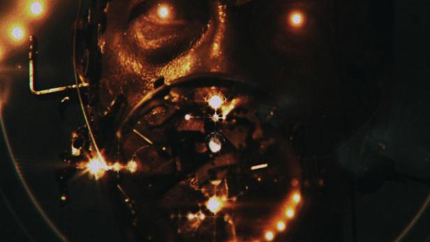 Das Gesicht einer Person, geschmückt mit goldenen Ornamenten und leuchtenden Augen, vor dem Hintergrund des Universums.