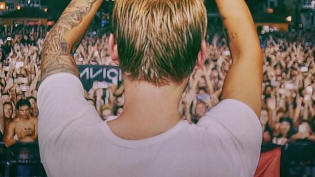 Avicii formt mit seinen Händen ein Herz vor einer jubelnden Menschenmenge bei seinem letzten Auftritt.