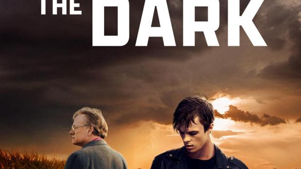 Das Filmplakat für „Brave the Dark“ zeigt zwei Männer vor einem roten Auto bei Sonnenuntergang.