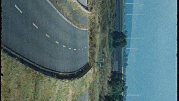 Das Filmplakat für „Hang am Baum“ zeigt eine leere, kurvige Straße.