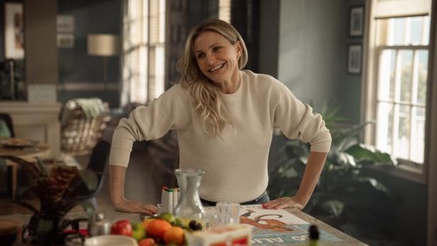 Cameron Diaz steht lächelnd in einer Küche und lehnt an einer Küchentheke.
