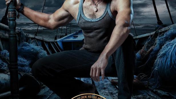 Ein bärtiger Mann sitzt auf einem Boot vor einem stürmischen Himmel.