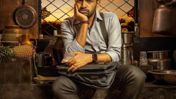 Ein Mann sitzt vor einem Fenster mit dem Schriftzug „PENN MAN“ darüber.