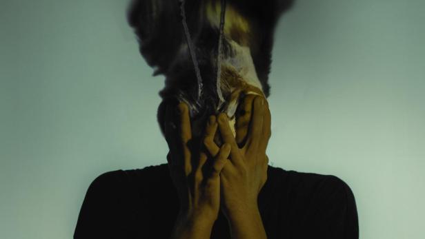 Ein Mann verdeckt sein Gesicht mit den Händen; Filmposter für „Schmetterling“.