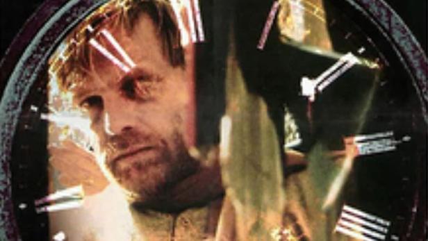 Ein Mann ist im Zifferblatt einer Uhr zu sehen, Titel: „The House of Clocks“.