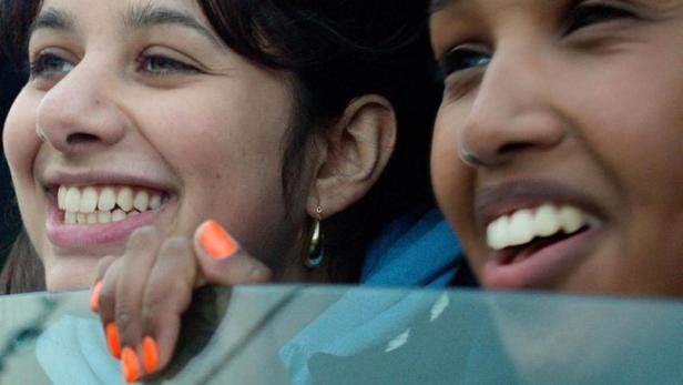 Zwei junge Frauen lächeln aus einem Autofenster; Filmposter für „Brides“.