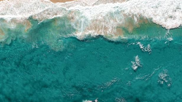Luftaufnahme eines Strandes mit türkisfarbenem Wasser und dem Titel „Hot Milk“.