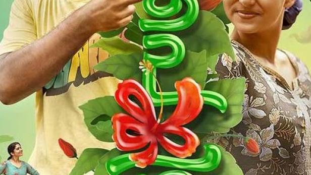 Ein Mann und eine Frau stehen vor einer grünen, blumengeschmückten Schrift.