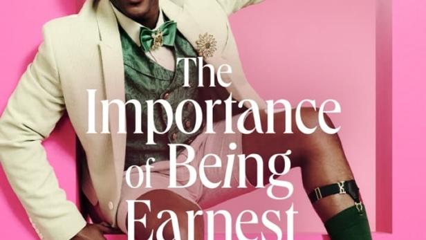 Ein Mann posiert in einem rosa Rahmen für eine Aufführung von „The Importance of Being Earnest“.