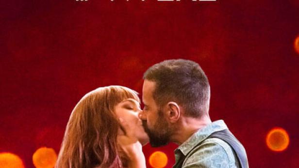 Ein Paar küsst sich vor dem Hintergrund des Filmplakats „Una Gran Voglia di Vivere“.