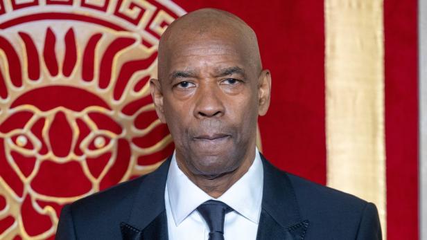 Porträt von Denzel Washington vor einem roten Hintergrund mit goldenen Verzierungen.