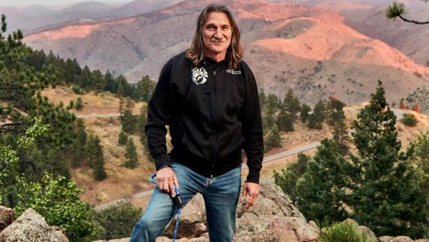 Dr. Jeff posiert mit seinem Golden Retriever vor einer Berglandschaft.