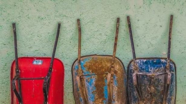 Drei Schubkarren in Rot, Braun und Blau stehen vor einer grünen Wand. Darüber steht der Text „Gemeinsam nüchtern“.