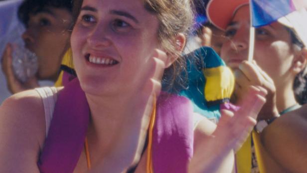 Eine lächelnde Frau klatscht inmitten einer Menschenmenge mit französischen Flaggen.