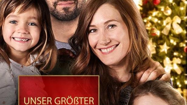 Das Filmplakat für „Unser größter Weihnachtswunsch“ zeigt eine glückliche Familie vor einem Weihnachtsbaum.