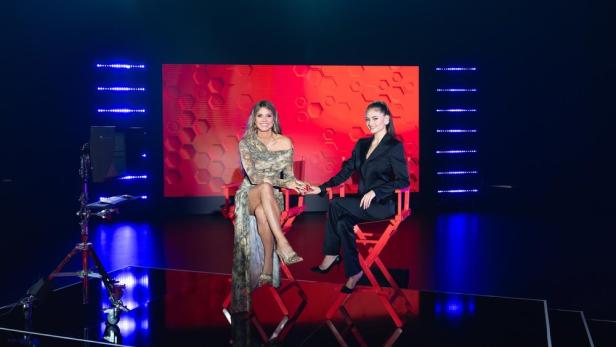 Heidi Klum und ihre Tochter Leni sitzen auf einem roten Stuhl bei GNTM 2025.