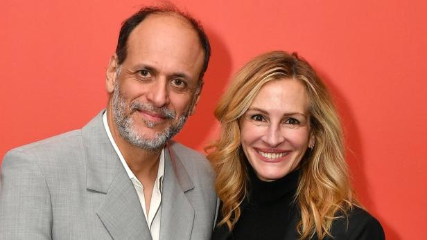 Der Regisseur Luca Guadagnino posiert mit Julia Roberts vor einem roten Hintergrund.