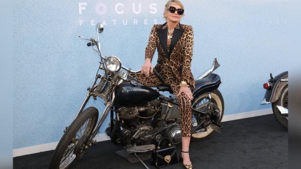 Sharon Stone posiert auf einem Motorrad in einem Leopardenmuster-Anzug.