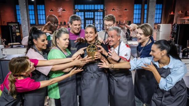 Eine Gruppe von Kandidaten umringt eine goldene Trophäe bei „Das große Promibacken“.