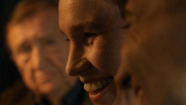 Das Filmplakat für „Nous les Prochains“ zeigt drei Personen, darunter eine lächelnde Frau.