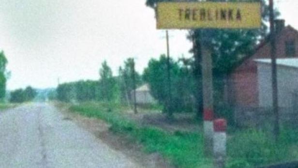 Blick aus einem Auto auf ein Ortsschild von Treblinka.