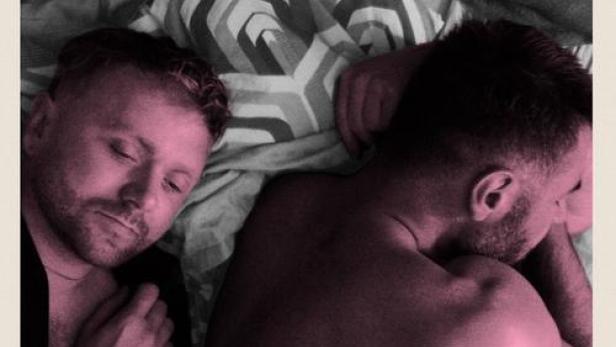 Filmplakat für „Departures“ mit zwei Männern, die im Bett liegen.
