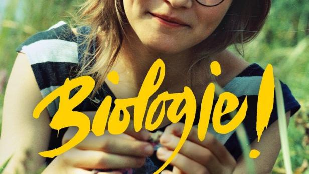 Ein junges Mädchen mit Brille hält eine kleine Blume in der Hand, im Vordergrund steht das Wort „Biologie!“.