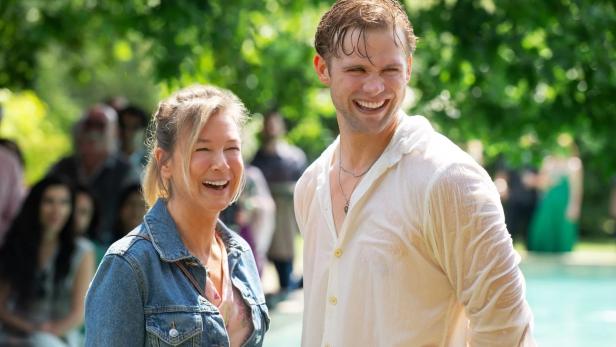 Renée Zellweger und Leo Woodall lachen zusammen vor einer Menschenmenge.