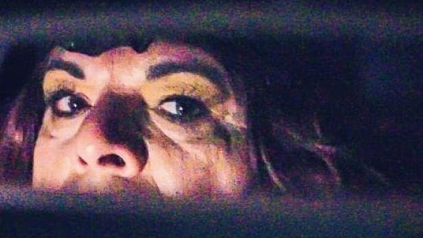 Das Filmplakat für „Zeit der Monster“ zeigt das Gesicht einer Frau, die durch einen Spalt blickt.