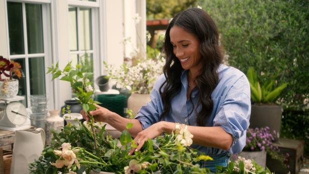 Meghan Markle arrangiert Blumen im Freien.