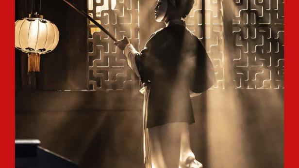 Eine maskierte Figur mit Laterne auf der Bühne der Royal Opera für „Turandot“.