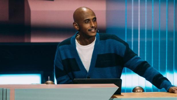 Teddy Teclebrhan steht an einem Tisch in einem Fernsehstudio.