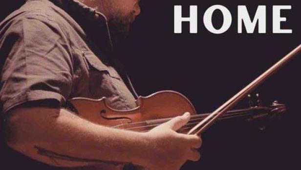 Ein Mann mit Brille spielt Geige; Filmposter für „The Road Home“.