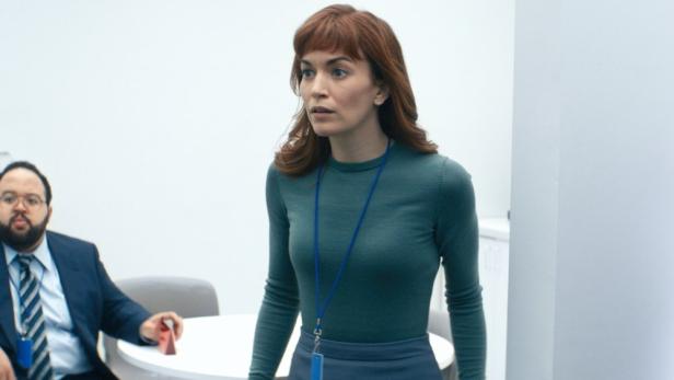 Eine Frau mit Namensschild in einer Büroumgebung, möglicherweise aus der Serie „Severance“.