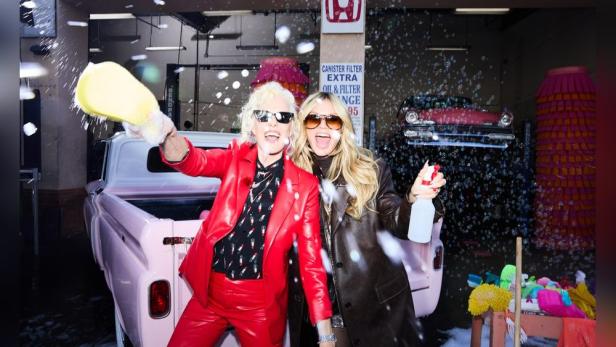 Ellen von Unwerth und Heidi Klum posieren in einer Autowaschanlage mit einem rosa Oldtimer-Truck.
