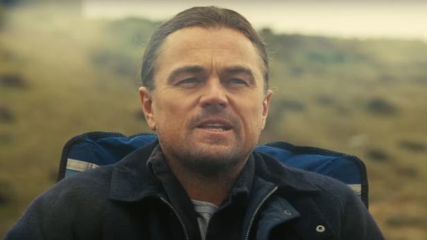 Leonardo DiCaprio sitzt in einem Stuhl vor einer Landschaft.