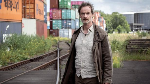 Ein Mann steht vor Güterwaggons auf einem verlassenen Gleis.