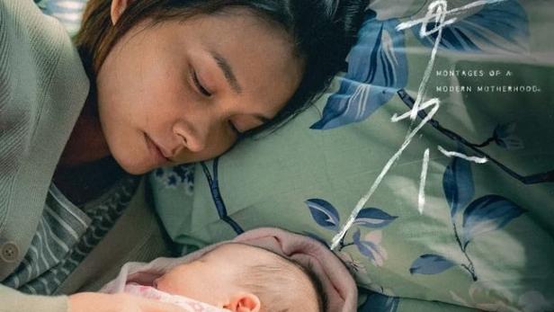 Eine Mutter schläft mit ihrem Baby auf einem blumigen Bettlaken.