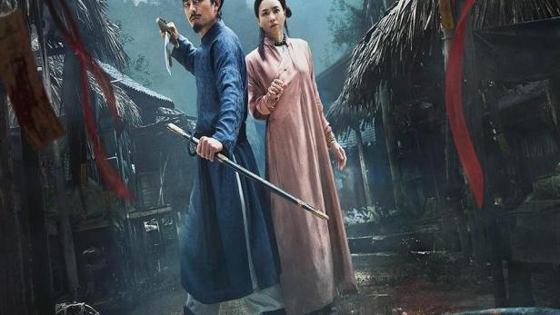 Ein Mann mit einem Messer und eine Frau mit einem Schwert stehen vor einem Dorf.